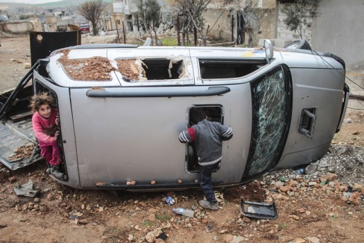 Un gruppo di bambini siriani gioca con un'auto distrutta nel centro di Kobane, in Siria. Foto scattata il 18 febbraio 2015